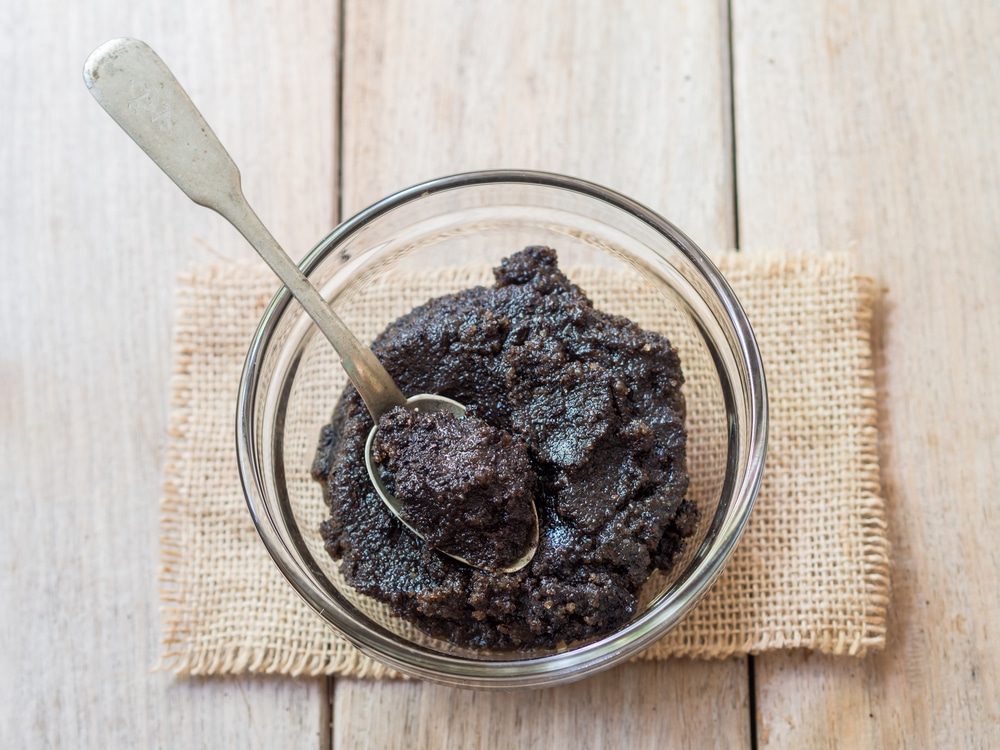 homemade coffee scrub in a glass jar with a spoon on a wooden table