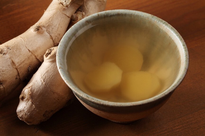 Cup of ginger tea and fresh ginger on a wooden table