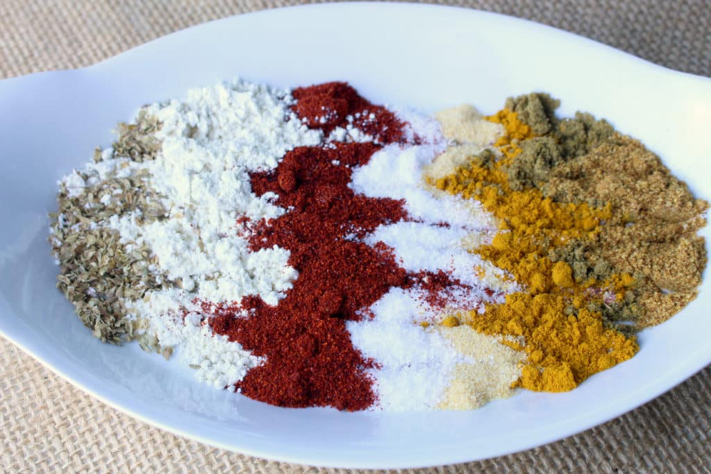 Individual spices lined up in a row in a bowl for taco seasoning