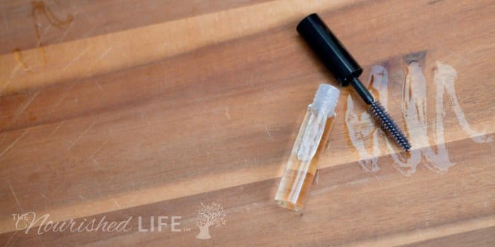 DIY Eyelash Growth Serum Recipe: mascara tube opened and spread serum on a bamboo board 