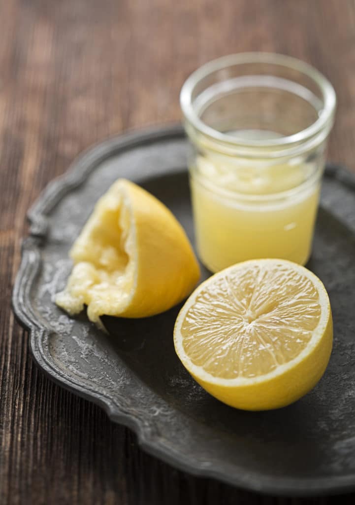 freshly squeezed lemon juice in a glass on a vintage plate