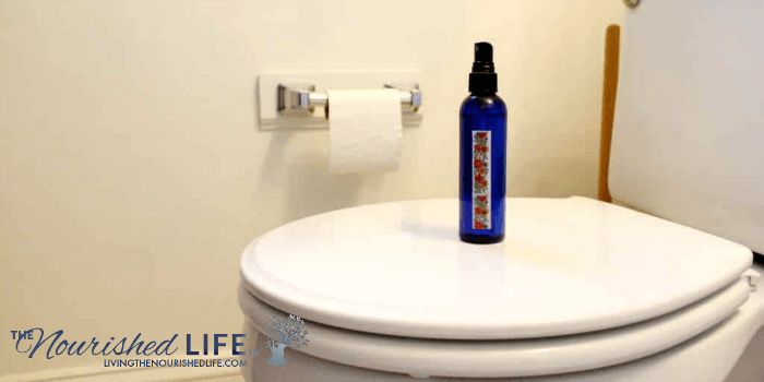 Natural DIY Poo Pourri Spray Recipe for Deodorizing Toilets: blue bottle on toilet seat