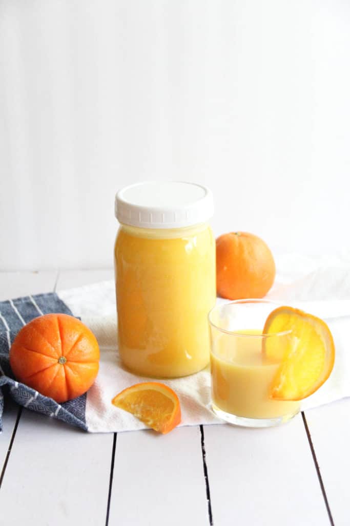 a mason jar of homemade electrolyte drink with orange slices on a white table