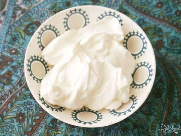 A small bowl of fluffy homemade foot cream on a blue printed tablecloth