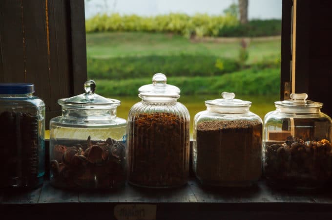 traditional herbs in glass jars in front of a window